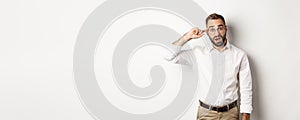 Confused man pointing at head, scolding employee, reaction on something strange, standing over white background