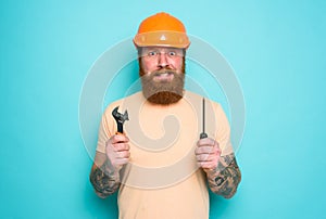 Confused man with screwdriver and spanners. worried and uncertain expression. cyan background