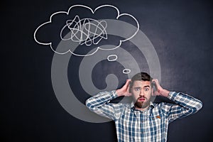 Confused man thinking about problem with black board behind him