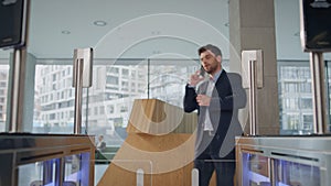 Confused man walking turnstile office talking smartphone. Man waving to screen