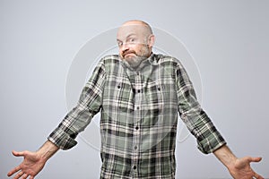 Confused mature bearded man standing and shrugging shoulders isolated over white background.