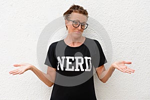 Confused mature nerd woman wearing big eyeglasses and standing against white background outdoors with raised arms