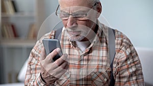 Confused old man looking at cellphone, new technology complicated for elderly