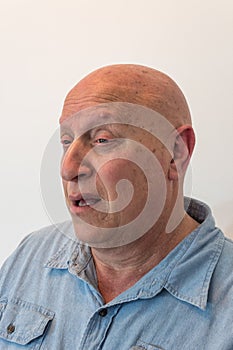 Confused older man who is bald, has alopecia, chemotherapy, cancer, on white