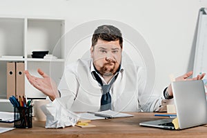 confused overweight businessman sitting at workspace with documents