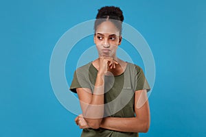 Confused pensive young african american woman girl in casual t-shirt posing isolated on bright blue background. People