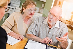 Confused Senior Adult Couple Going Over Documents in Their Home with Agent At Signing