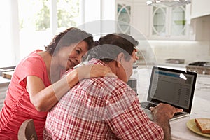 Confused Senior Hispanic Couple Sitting At Home Using Laptop