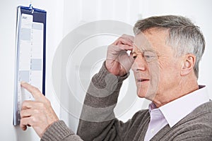 Confused Senior Man With Dementia Looking At Wall Calendar