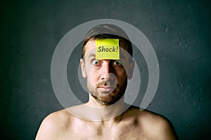 Confused shocked man with yellow sticky note on his forehead