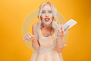 Confused shocked young blonde woman using mobile phone.