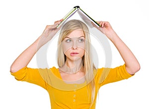 Confused student girl with raised book over head