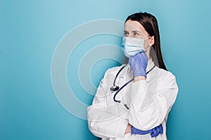 Confused and thoughtful female doctor, nurse in protective mask and gloves thinking, looking away indecisive