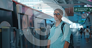 Confused tourist takes off backpack to enter arriving subway car. Man arrived in unfamiliar city and decided to use