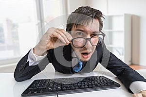 Confused or unsure man is working with computer and looking at you photo