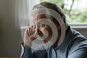 Confused upset old 70s aged man rubbing face and eye