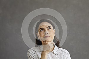 Confused woman full of doubt looking up and thinking trying to make choice or answer question