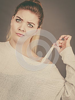 Confused woman holding her bra strap