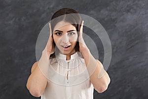 Confused woman puts her hands on ears