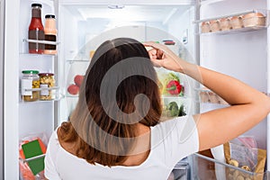 Confused Woman Searching For Food In The Fridge