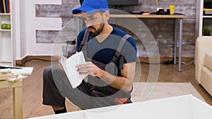 Confused worker in overalls reading instructions