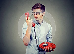 Confused worried man looking at old fashioned telephone