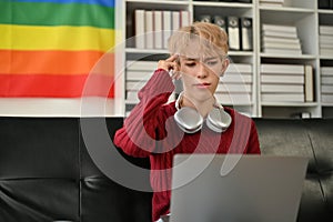 A confused young Asian gay man is using a laptop and trying to solve the problem