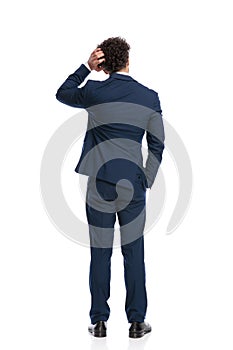 Confused young businessman scratching head and thinking