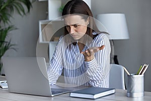 Confused young businesswoman looking at computer screen.