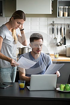 Confused young couple worried checking domestic bills having fin