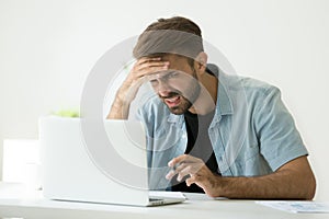 Zmatený mladý muž frustrovaný podle připojen do internetové sítě kouká na note 