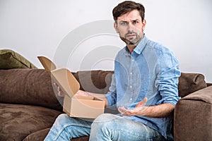 Confused young man getting poor quality goods from online shop