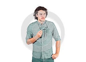 Confused young man, long curly hair style, holds eyeglasses in his hand, thoughtful gesture, looking suspicious aside isolated on photo