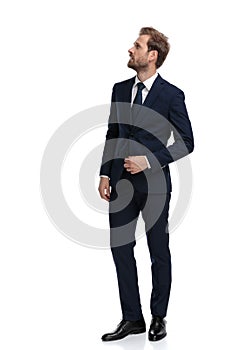 Confused young man in navy blue suit looking up