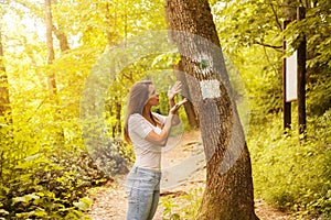 Confused young woman looking at a sign in the forest