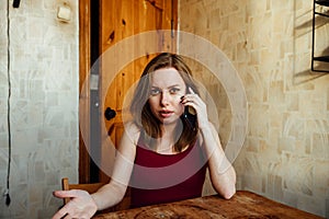 A confusing girl sits at the chair with a phone in her hands waiting for a call