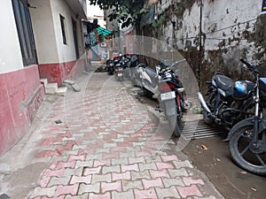 a congested path lined with irregularly parked two wheeler bikes