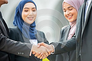 Congratulations! Muslim Asian business people shakes hand.
