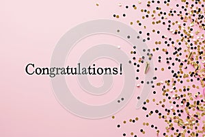Congratulations text on pastel pink background with gold confetti