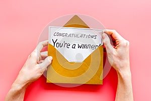 Congratulations You`re a winner. Hands holding envelope with letter. Pink background top view