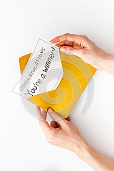 Congratulations You`re a winner. Hands holding envelope with letter. White background top view