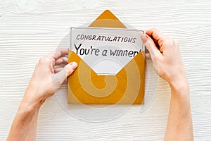 Congratulations You`re a winner. Hands holding envelope with letter. White wooden background top view