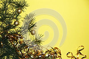 Coniferous branches and Christmas tree decorations on a New Year`s yellow background, copy space