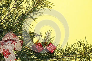 Coniferous branches and Christmas tree decorations on a New Year`s yellow background, copy space