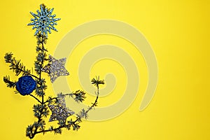 Coniferous branches and Christmas tree decorations on a New Year`s yellow background, copy space