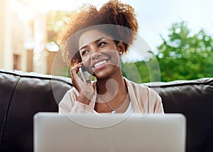 Connect and catchup. a happy young woman using her phone and laptop on the sofa at home.