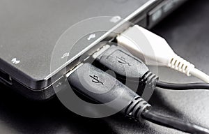 Connect three USB cable to laptop computer on black desk.