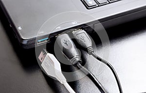 Connect USB cable to laptop computer on black desk.