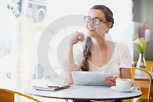 Connected and caffeinated. a relaxed young woman using her tablet while drinking coffee at her favorite cafe.