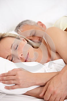 Connected and intimate. Cropped closeup of a mature couple embracing while sleeping peacefully next to each other.